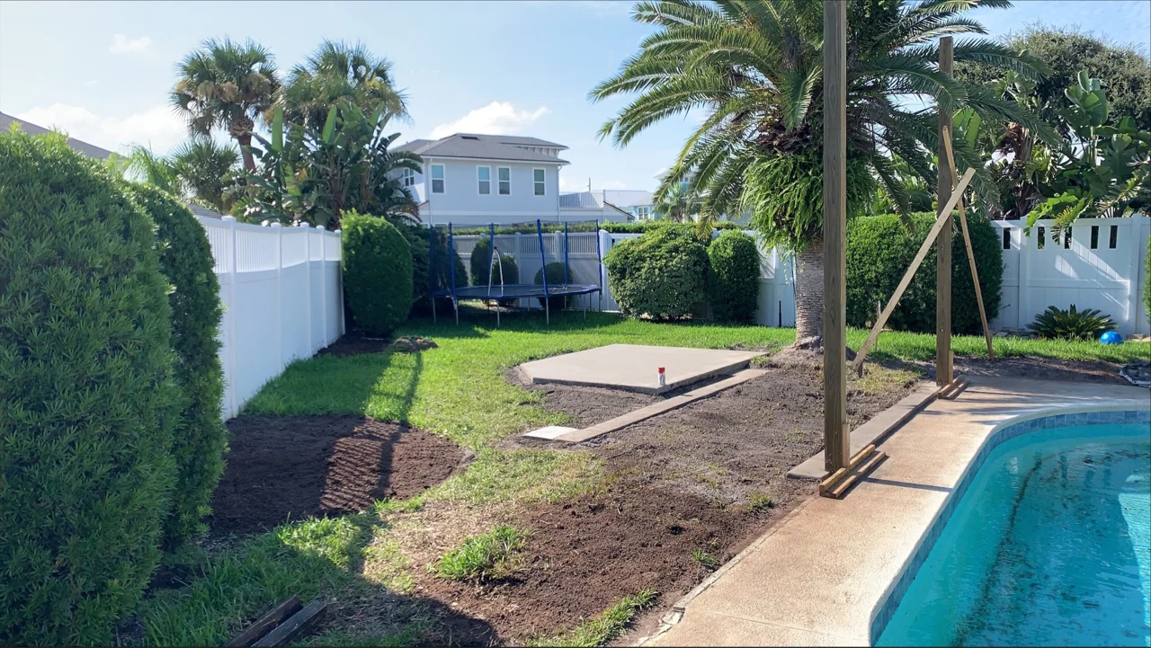 Backyard with pool, grass, garden beds, white fence, and a two-story white house.