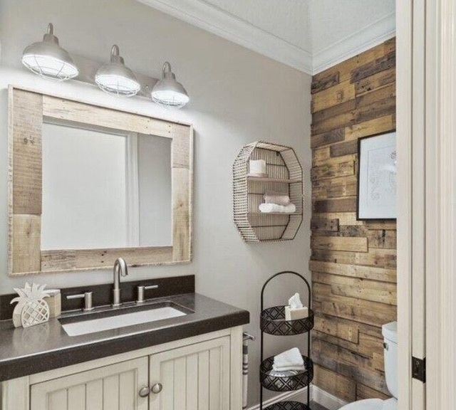 Bathroom with rustic wood accent wall, framed mirror, and decorative metal shelves.