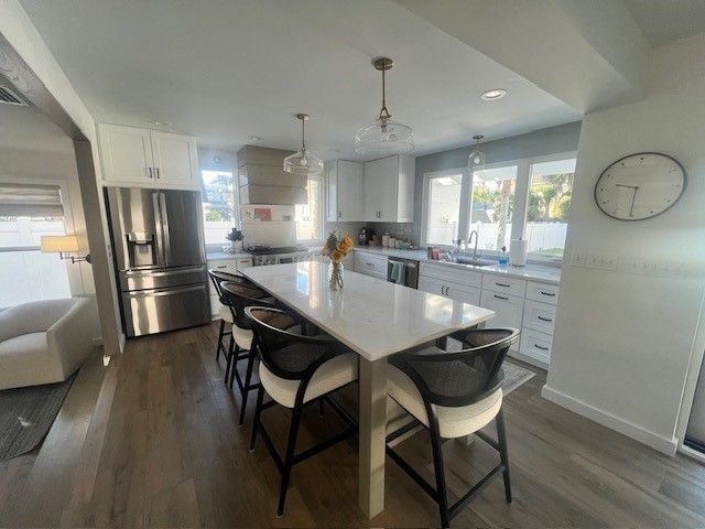 Modern kitchen with a white island, white cabinets, and stainless steel appliances.