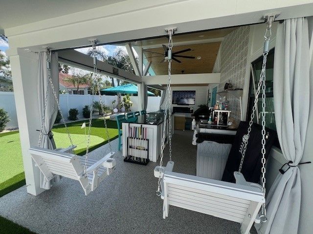 Outdoor patio with white swings, gray curtains, and artificial turf lawn.