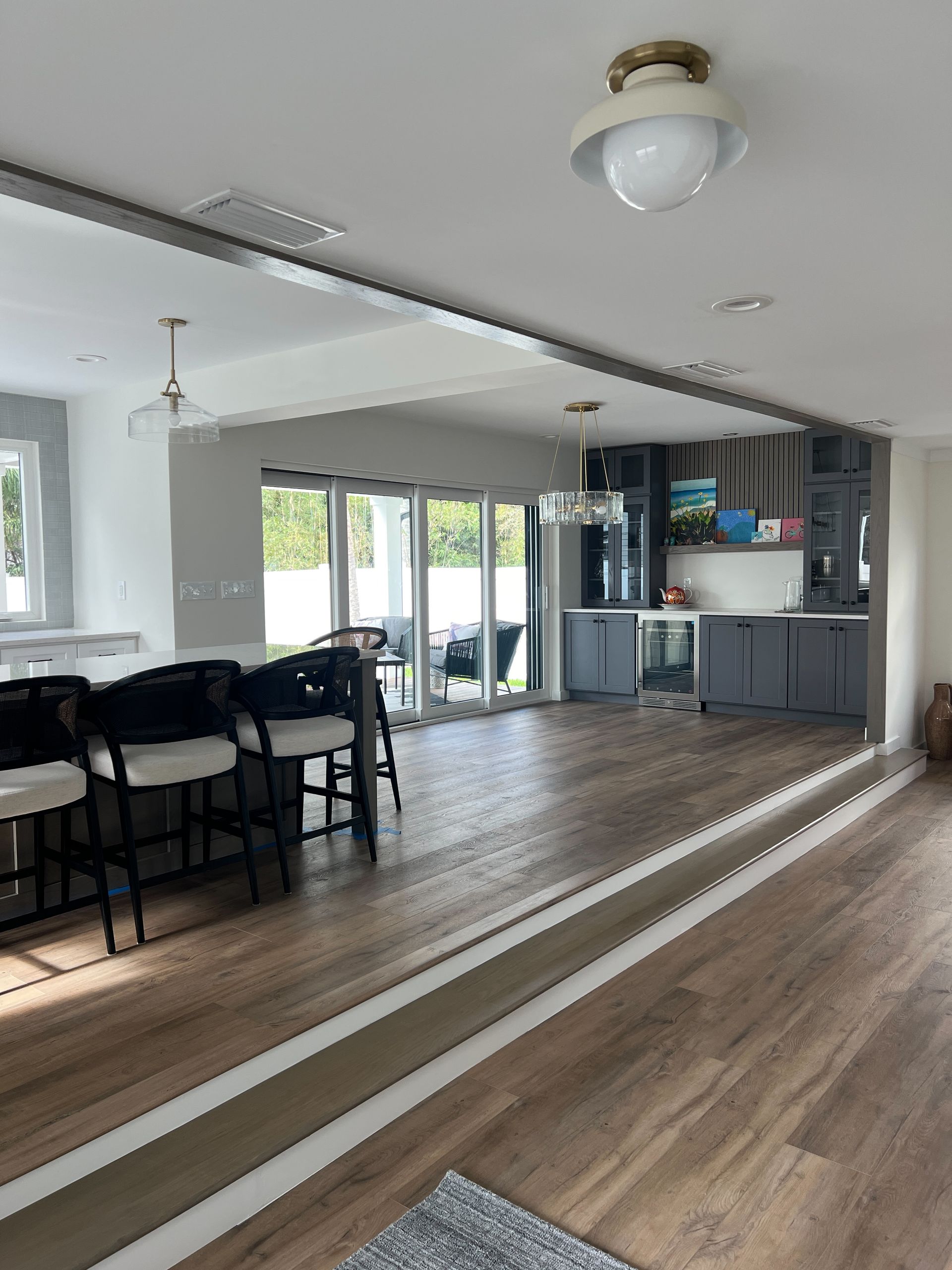 Bright modern room with wood floors, mirrored wall, black chairs, and a compact kitchen area.