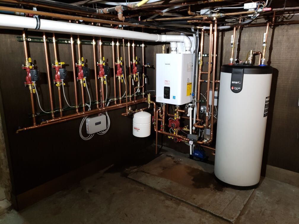 Basement boiler room with pipes, valves, water heater, and utility equipment on a concrete floor