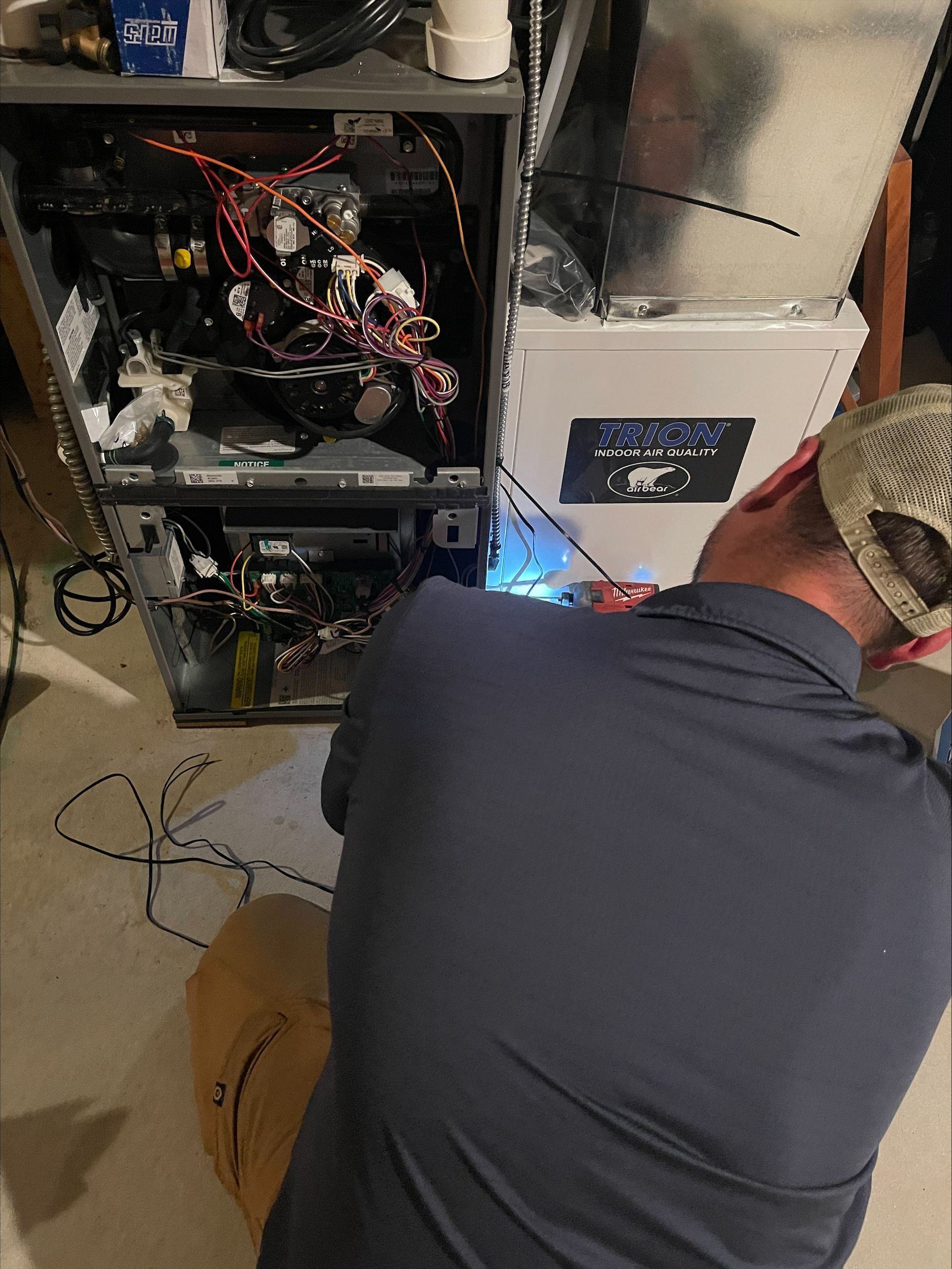 Technician kneels beside an open computer tower, working on cables next to a silver server rack.