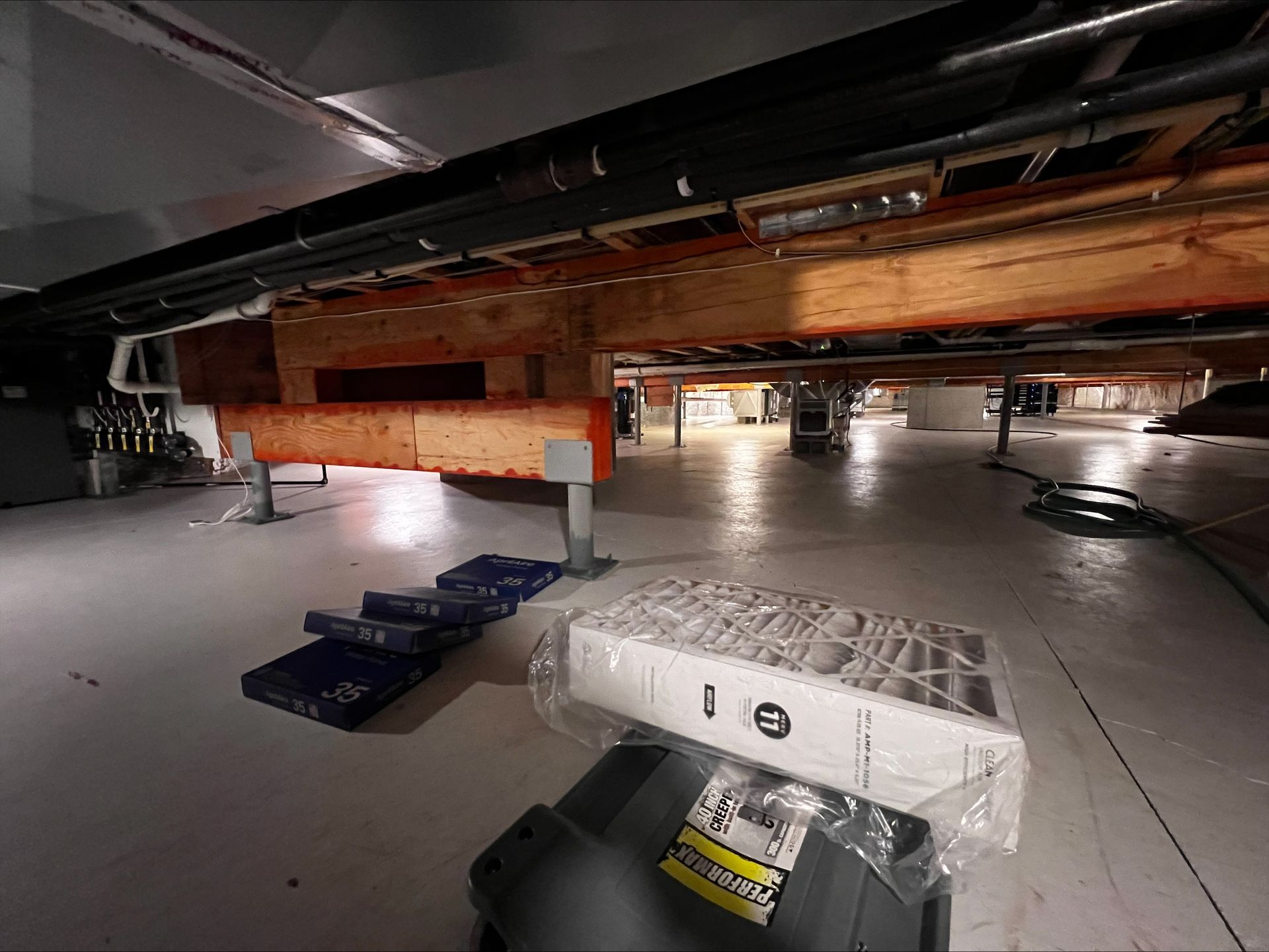 Low-angle view of a vehicle lifted in a garage, with tools and equipment underneath.