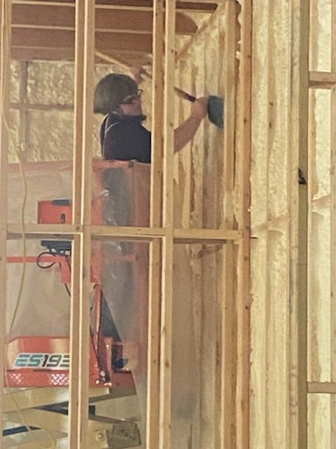 A man is standing on a lift working on a wall.