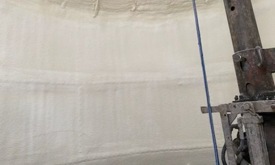 A person is spraying foam on a wall in a room.