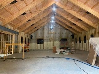 A large room with a vaulted ceiling and wooden beams is being built.