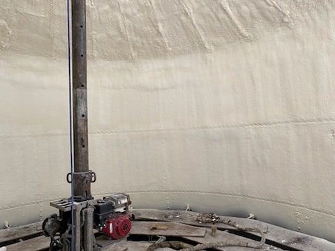 A large metal pipe is sitting inside of a large concrete tank.