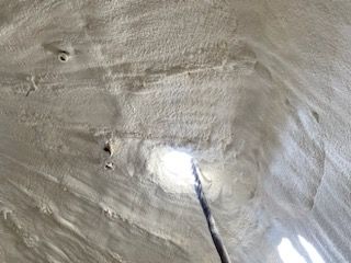 A person is spraying foam on the ceiling of a building.