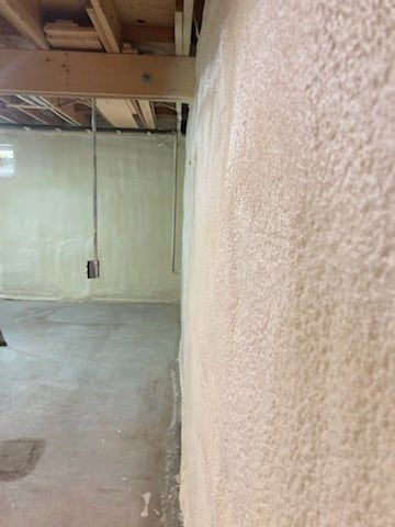 A basement with a wall covered in spray foam.