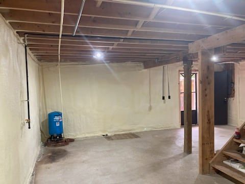An empty basement with a water tank and stairs.