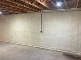 A basement with a wall covered in spray foam.