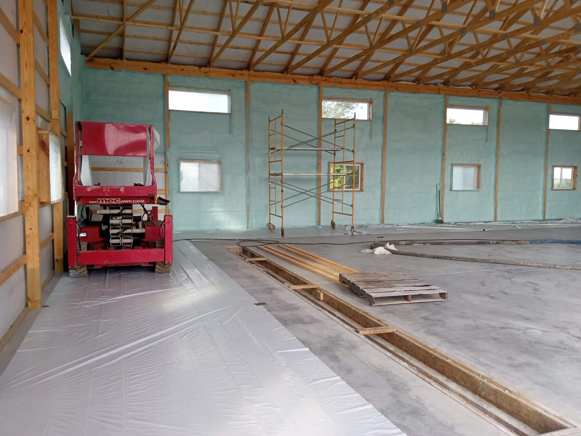 A red scissor lift is parked inside of a building under construction.