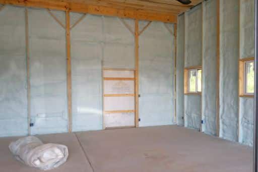 An empty room with a roll of insulation on the floor.