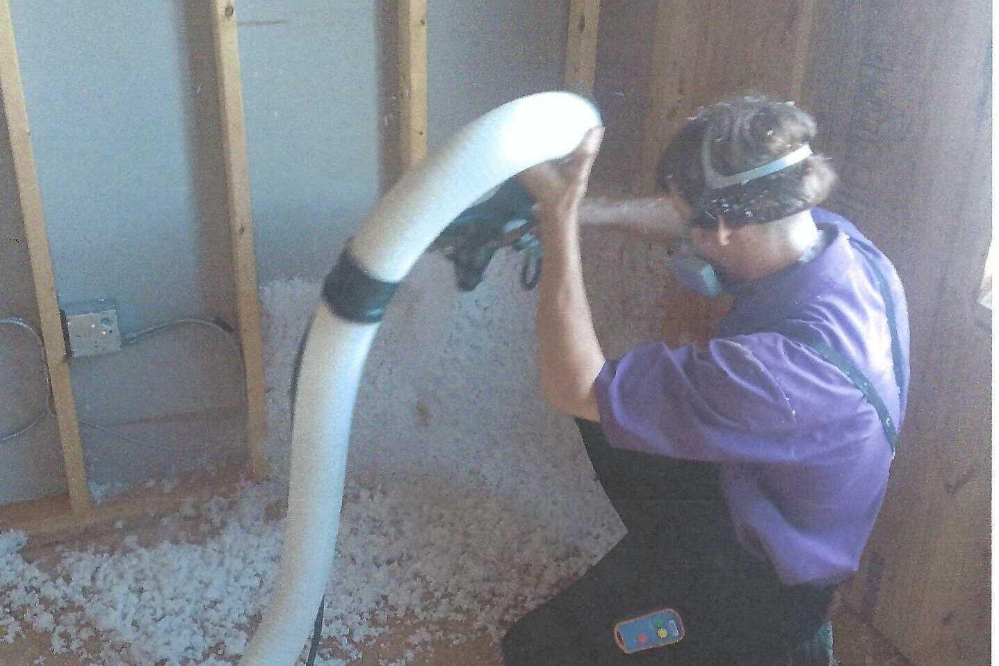 A man is kneeling down in a room with a hose attached to him.