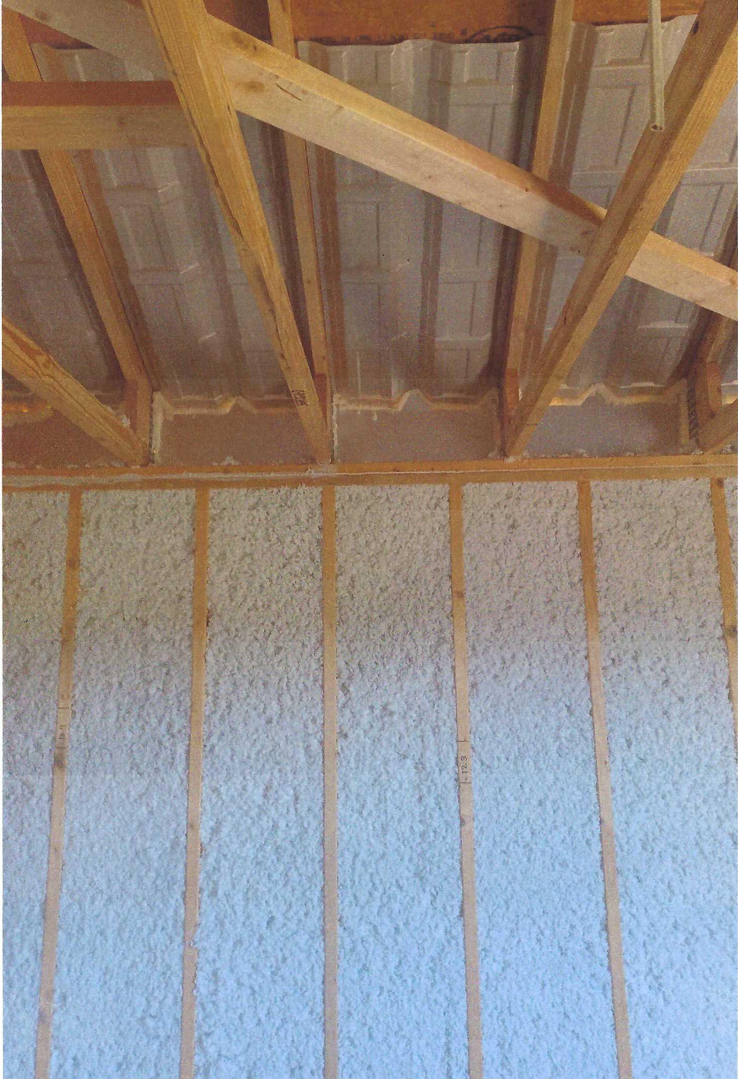 A picture of the inside of a building with wooden beams and insulation.