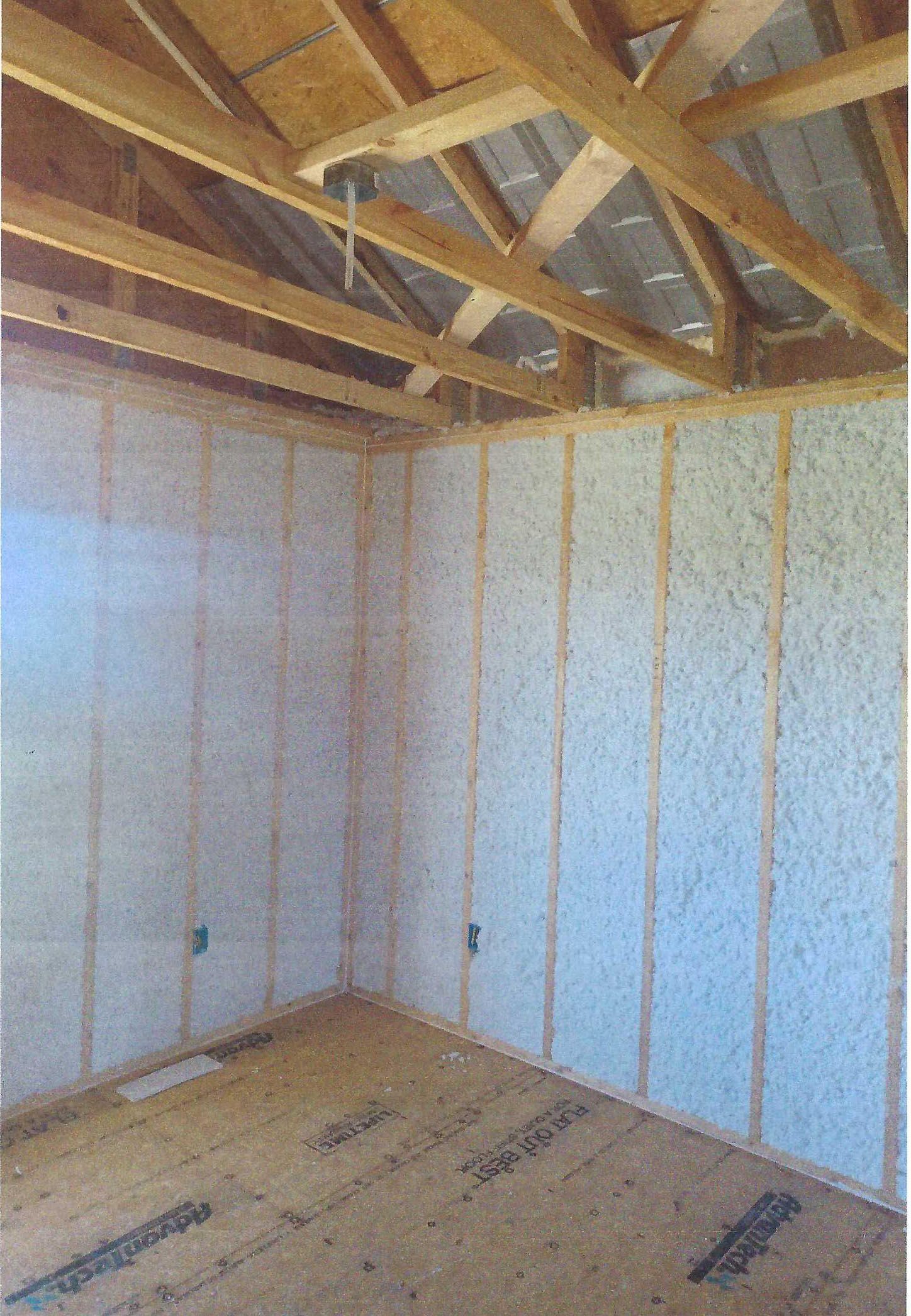 A room with wooden walls and a wooden floor under a roof.