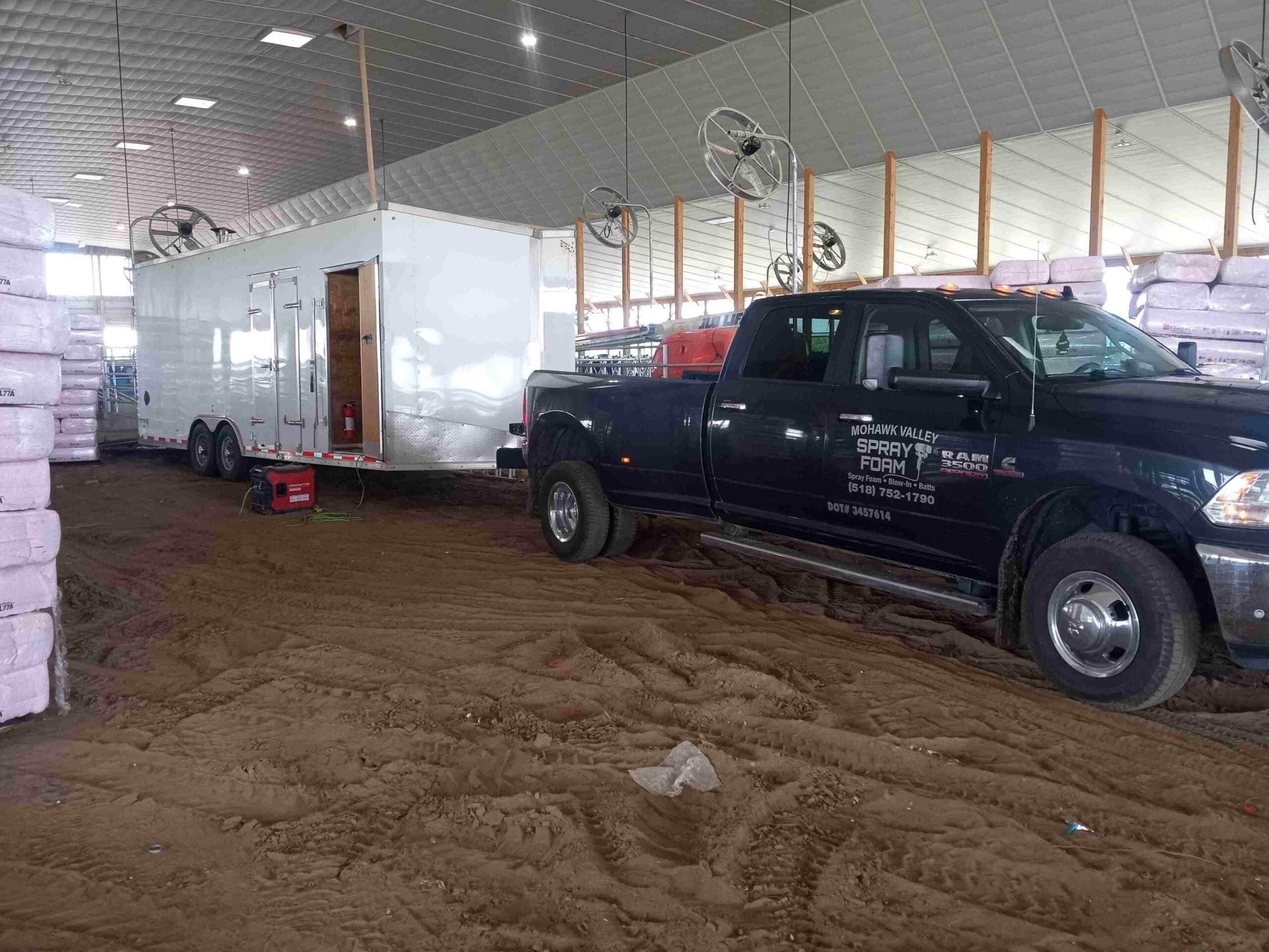 A truck is parked in a warehouse next to a trailer.