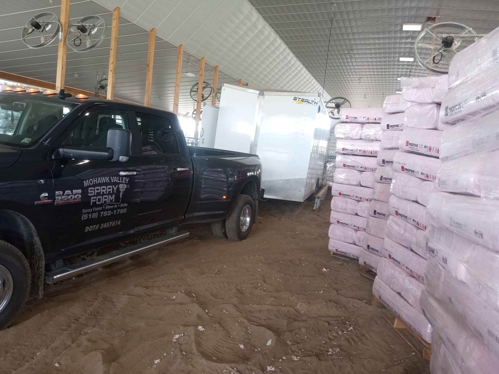 A black truck is parked in a warehouse next to a trailer.