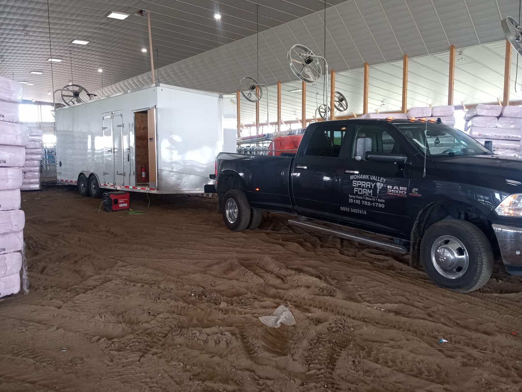 A truck is parked in a warehouse next to a trailer.