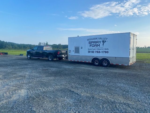 A truck is towing a trailer in a gravel lot.