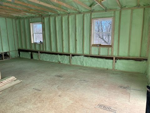 A room with green insulation on the walls and a window.