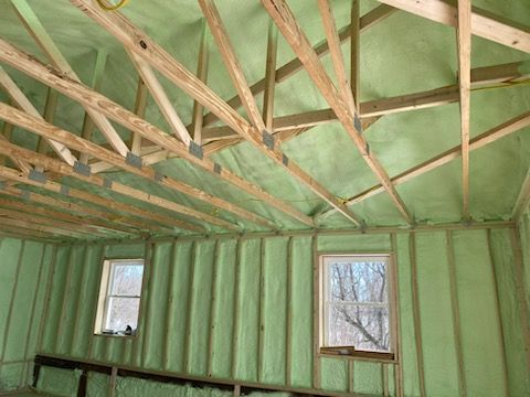A room with green insulation and wooden beams.
