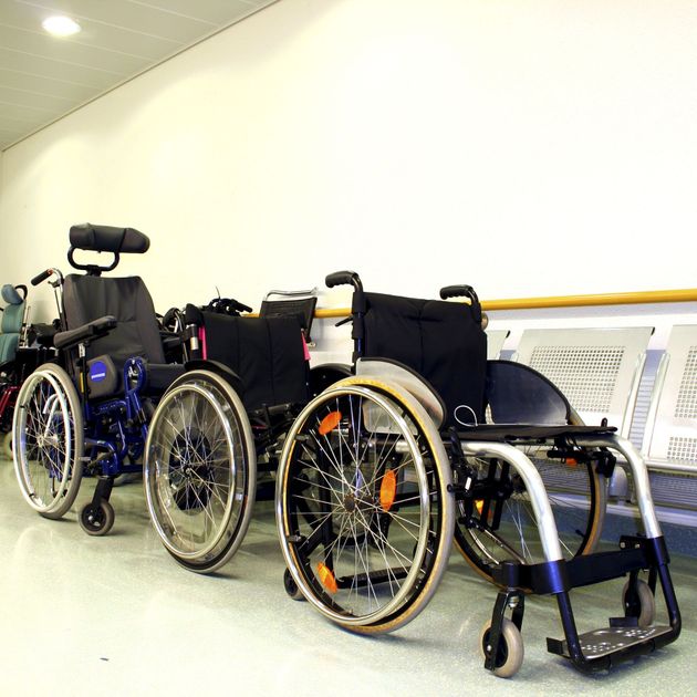 Several wheelchairs lined up in a hallway, showing different wheel sizes and frames.