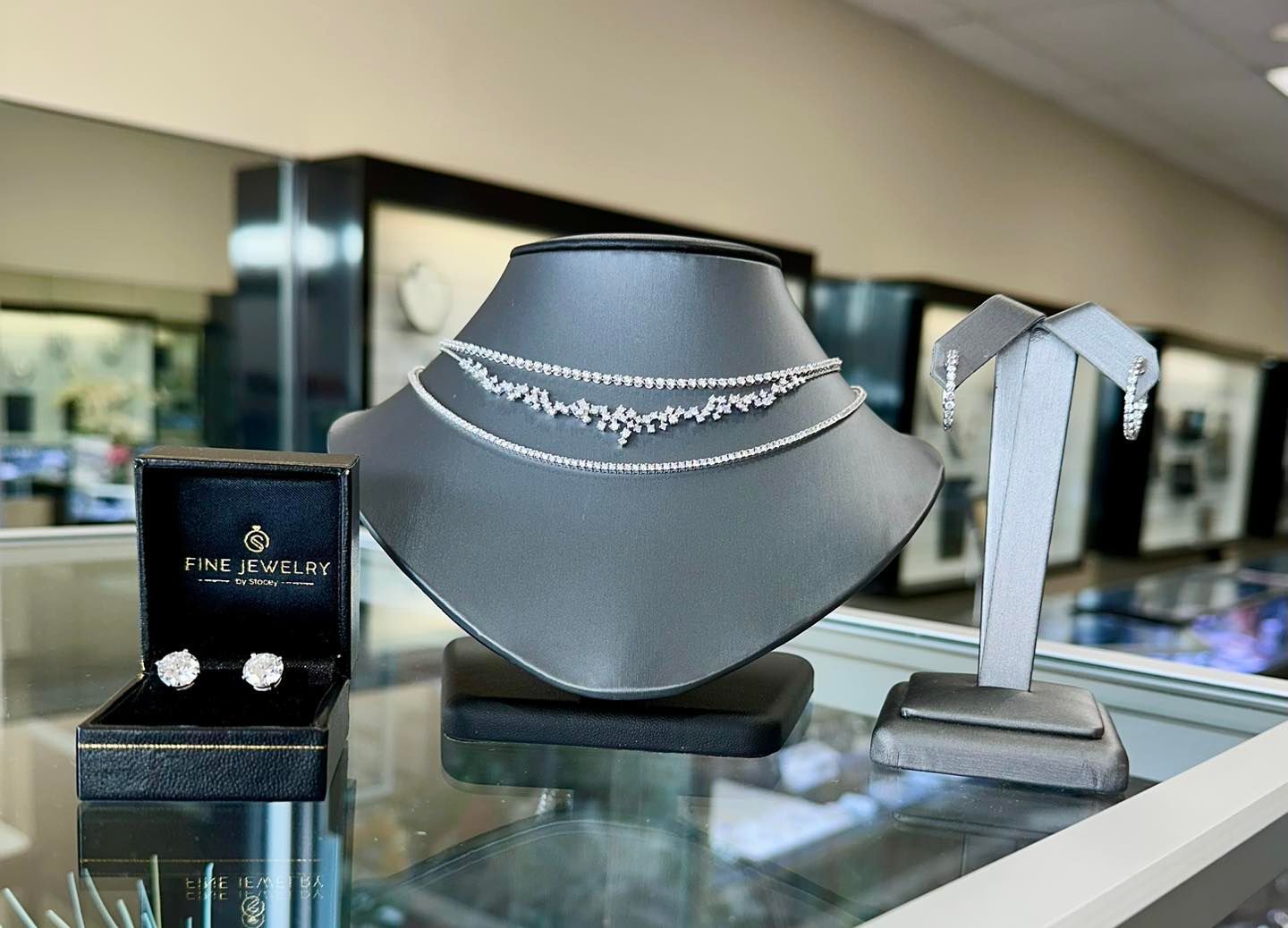 Jewelry display: diamond necklace, earrings, in a store with glass cases.