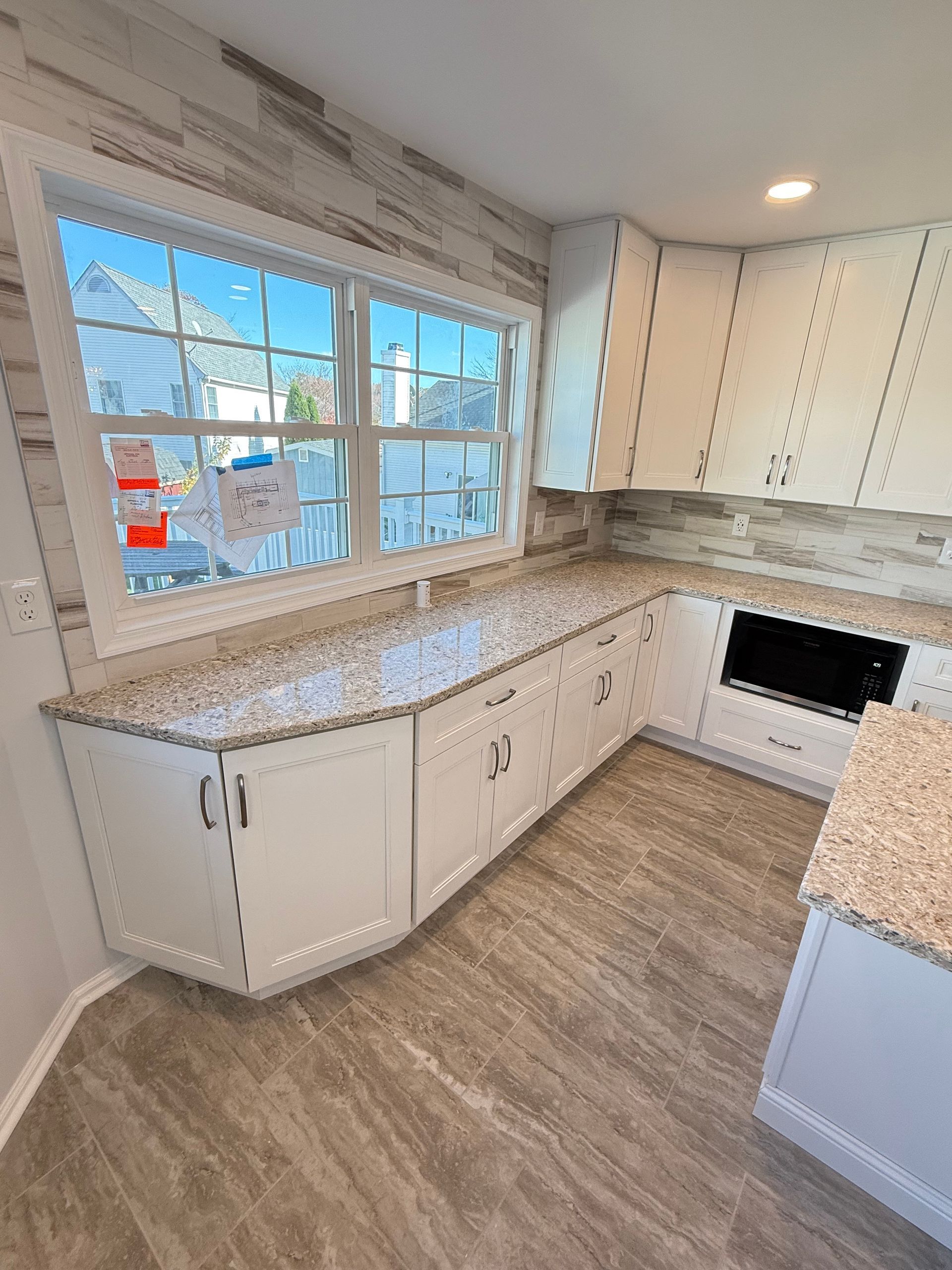 White kitchen with a window and granite countertops.
