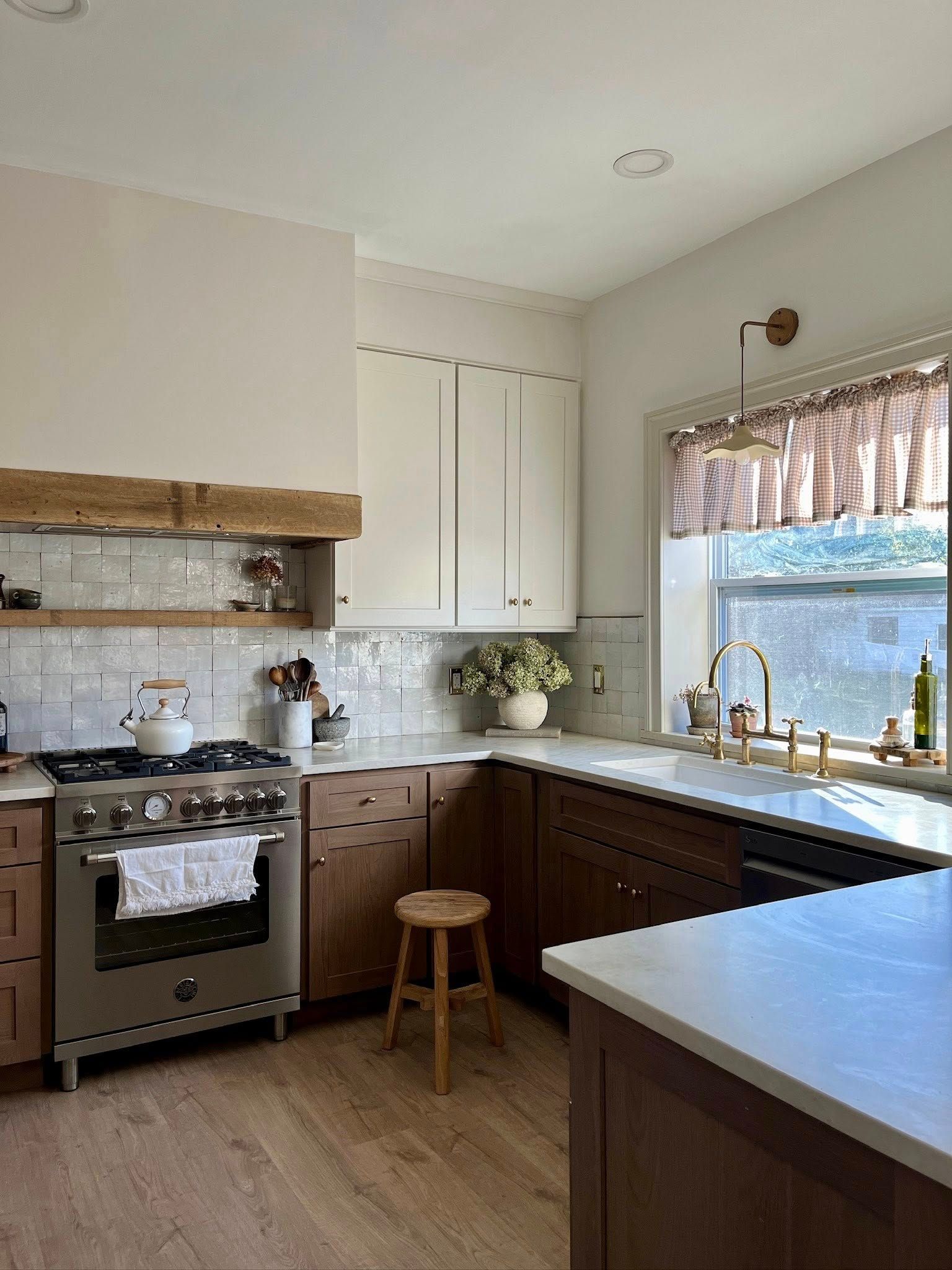 Kitchen with two-tone cabinets, stainless steel range, white countertops, and wood floors.