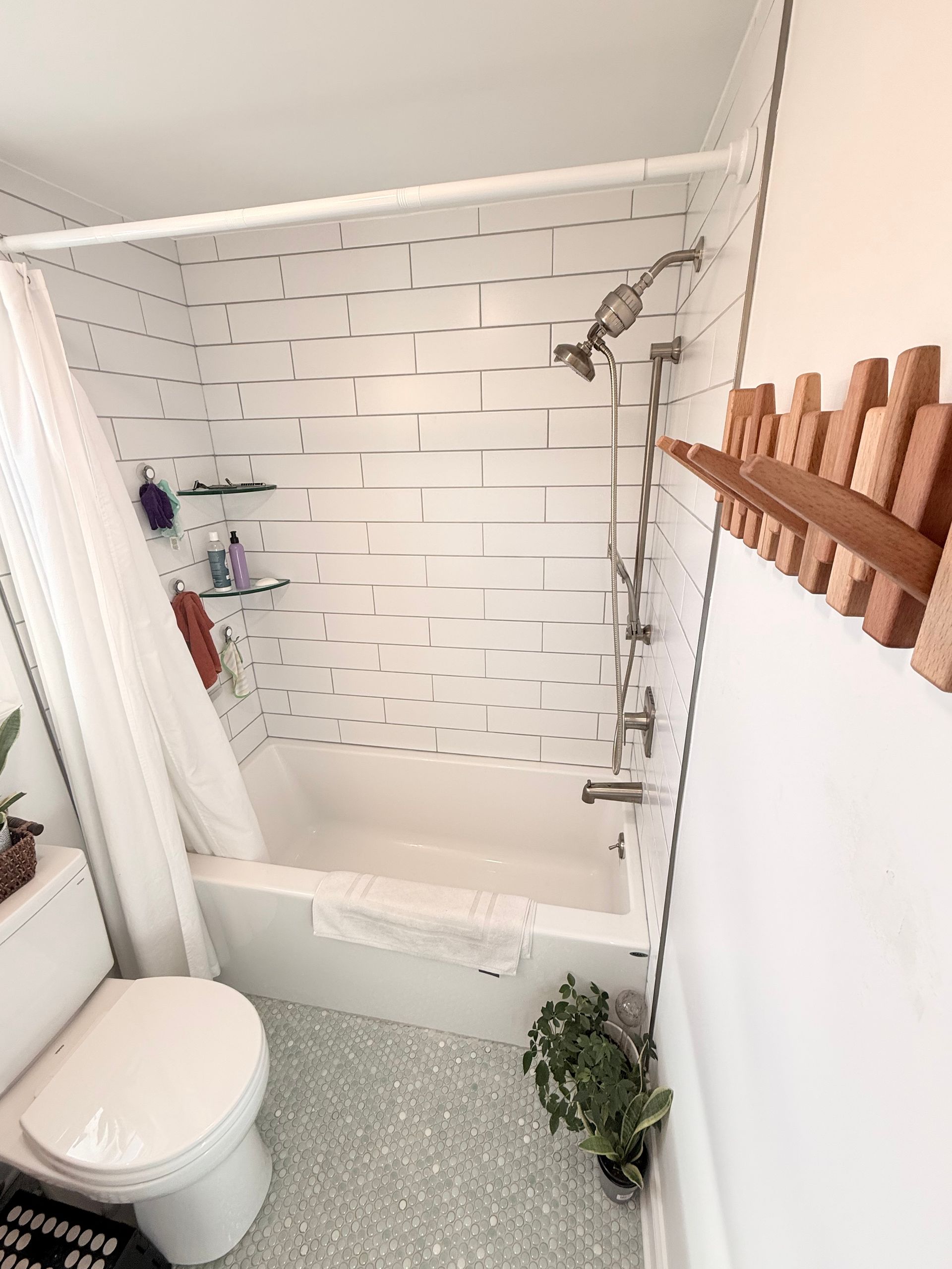 Small bathroom with white subway tile shower, toilet, and terrazzo floor.