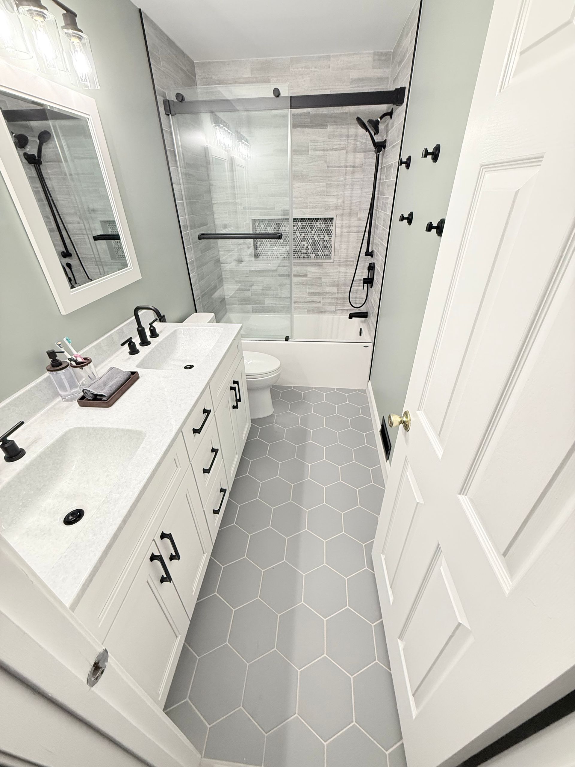 Bathroom with light gray hexagon tile floor, white vanity, and glass shower.