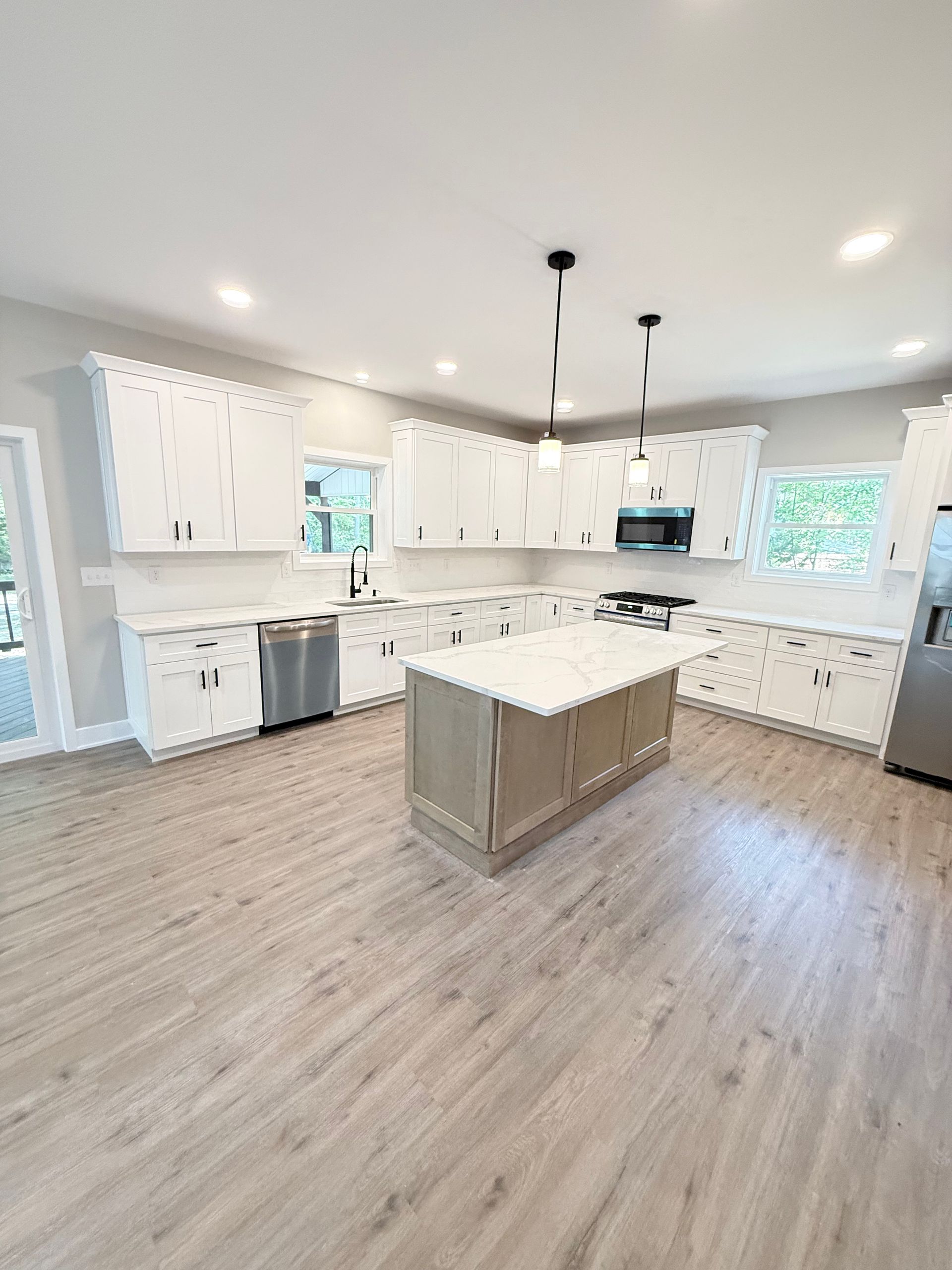 Bright, modern kitchen with white cabinets, light wood floors, and a gray island.