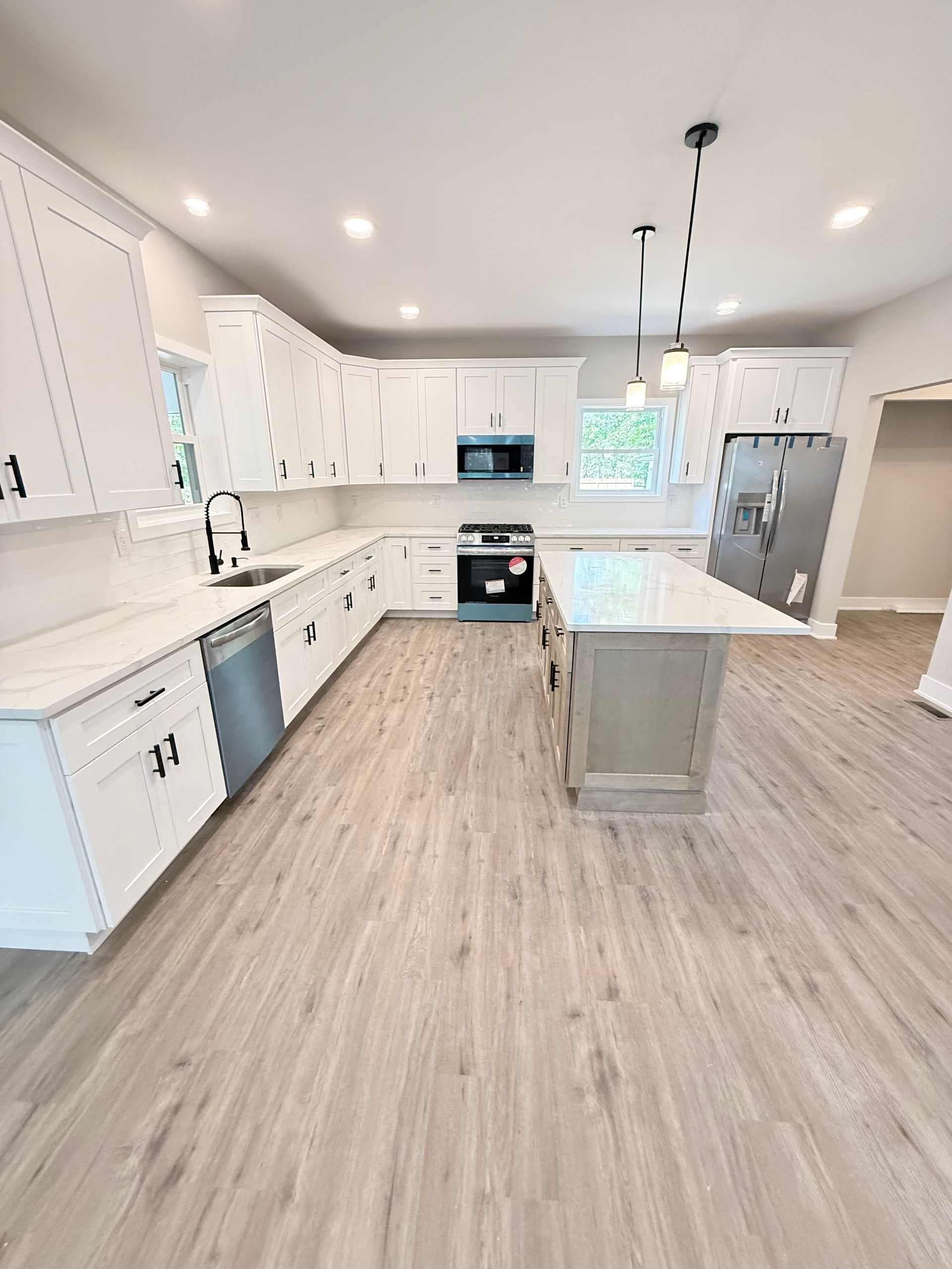 White kitchen with island, cabinets, appliances, and light wood flooring.