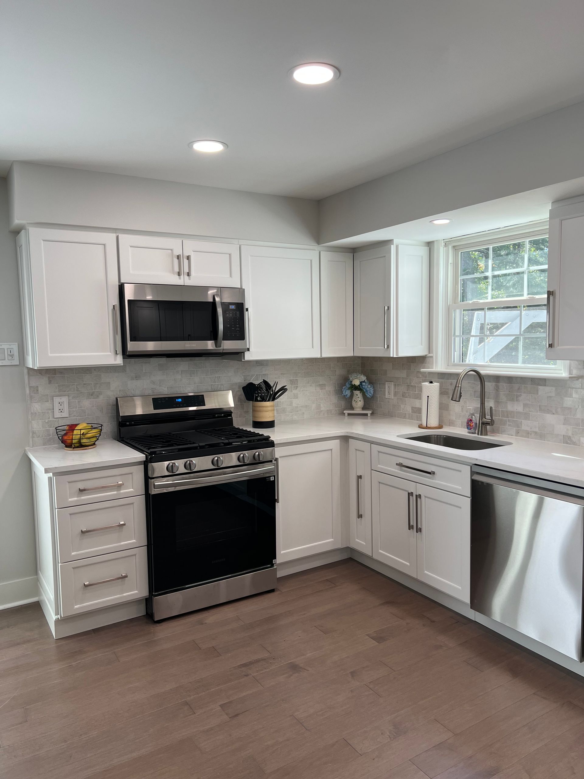 White kitchen with stainless steel appliances, white cabinets, and light countertops.