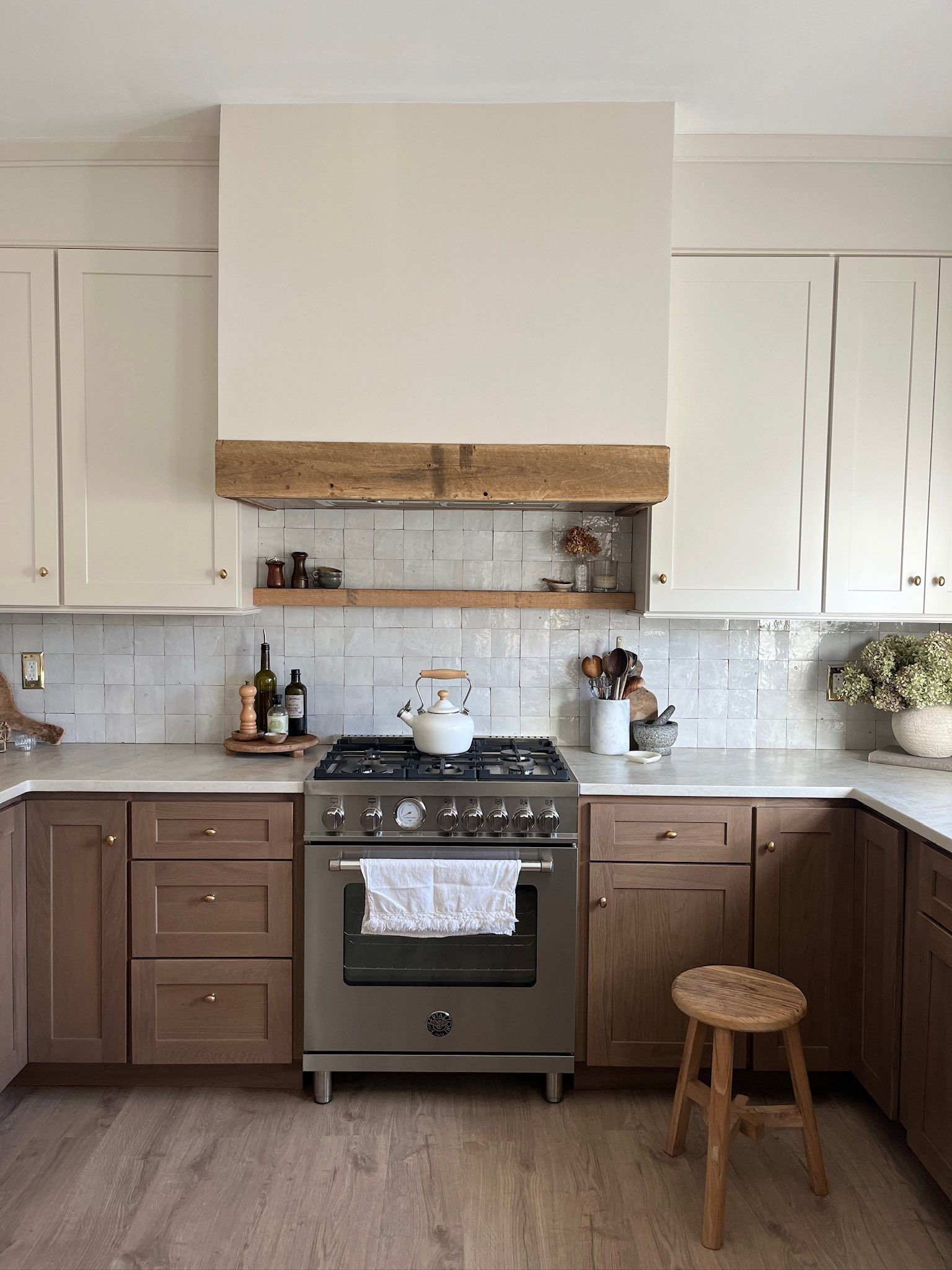 Rustic kitchen with white and brown cabinets, stainless steel stove, and wooden accents.