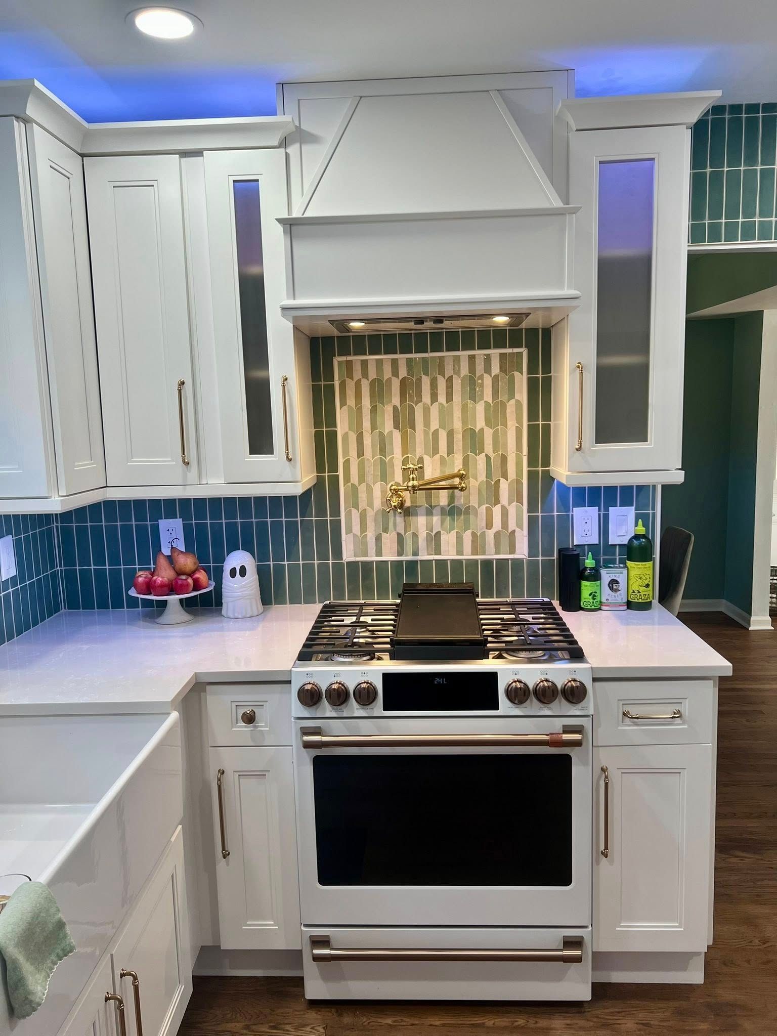 White kitchen with range, hood, and aqua tile backsplash.