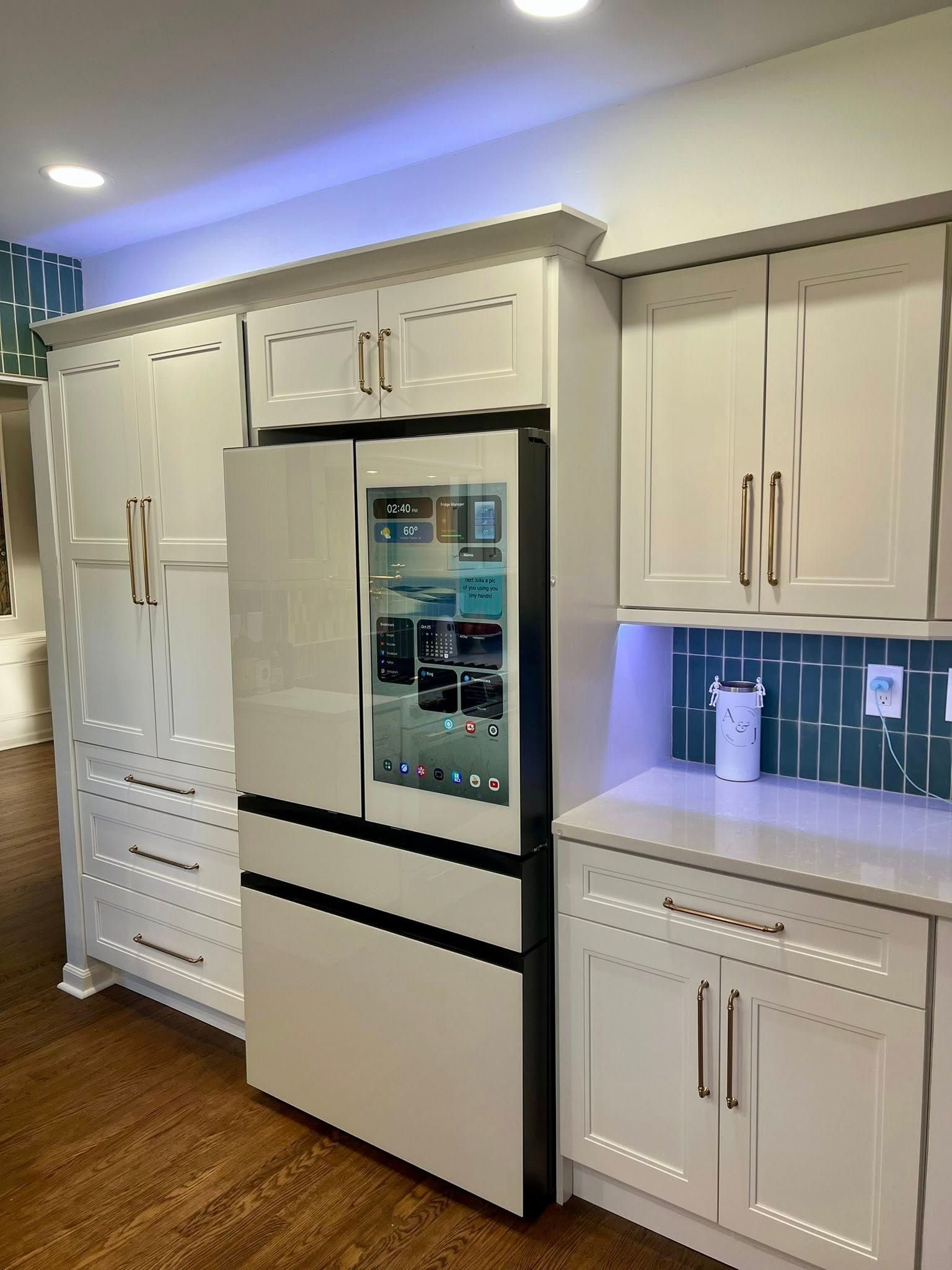 White kitchen with built-in refrigerator, cabinets, and blue tile backsplash.