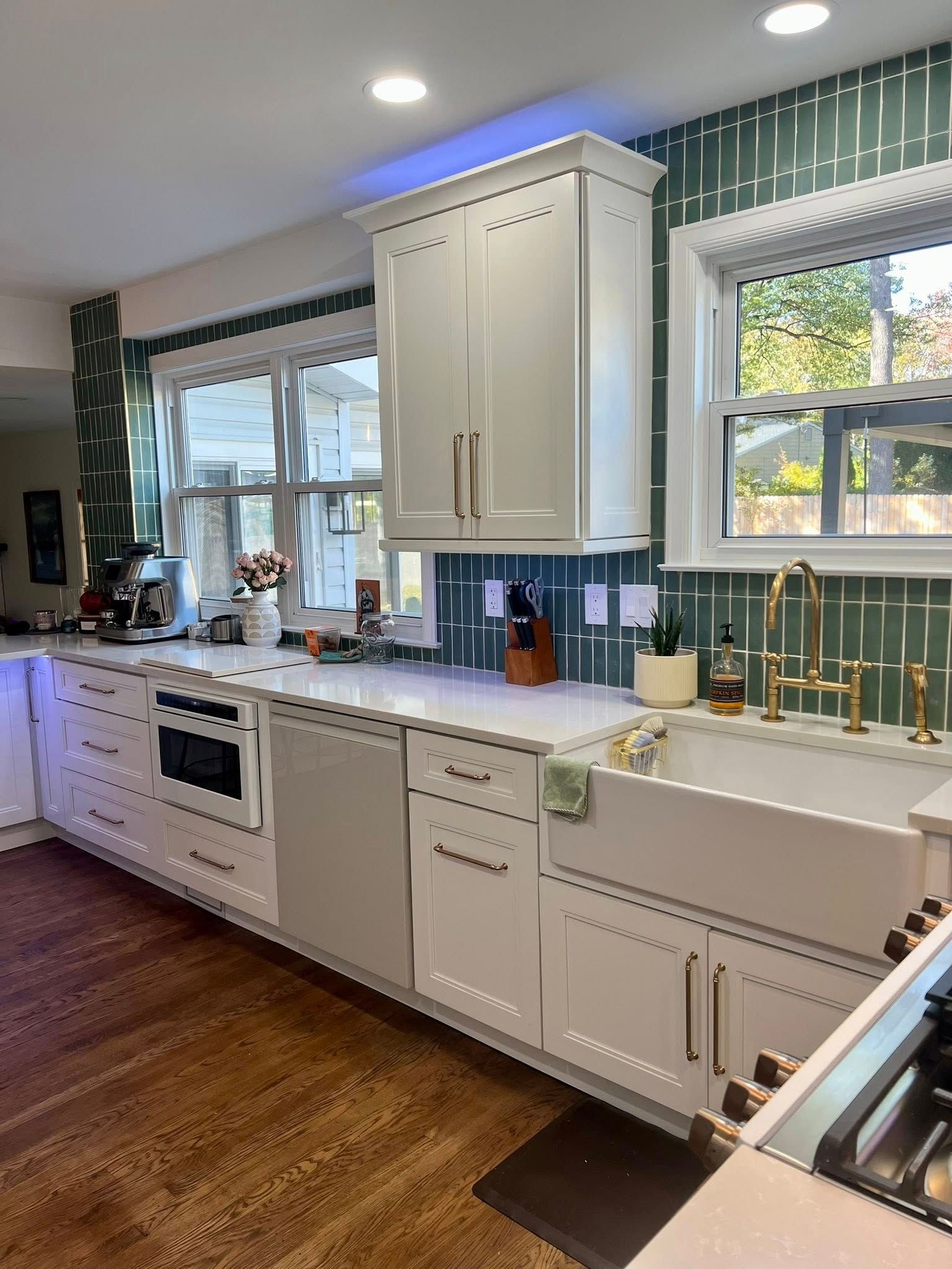 Modern kitchen with white cabinets, green tile backsplash, and a farmhouse sink.