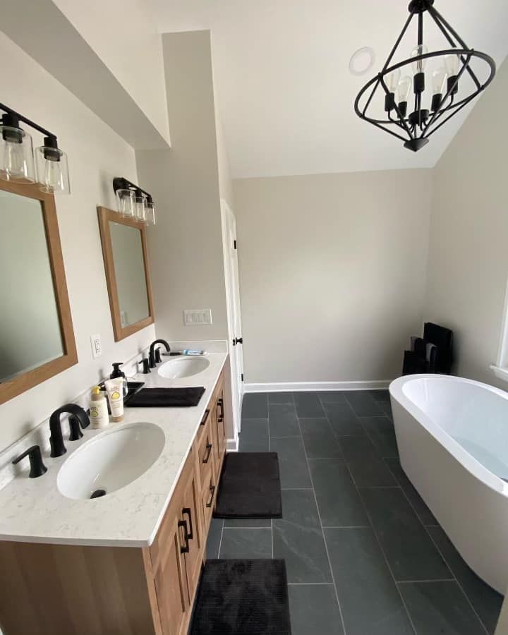 Bathroom with dual vanity, freestanding tub, and dark gray tile floor.