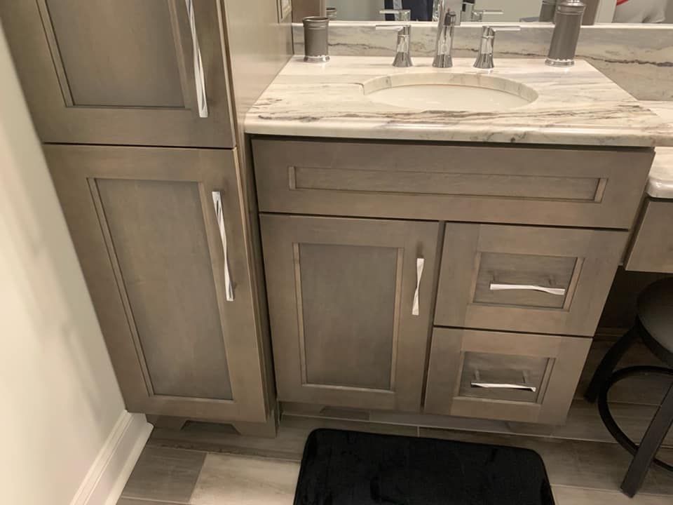Bathroom vanity with gray cabinets, marble countertop, and silver fixtures.