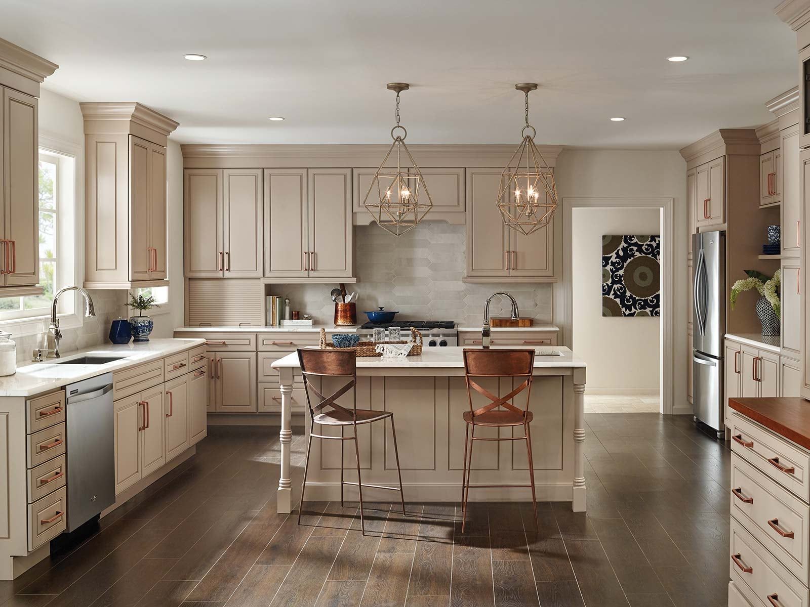 A kitchen with light cabinets, an island with bar stools, and two pendant lights.