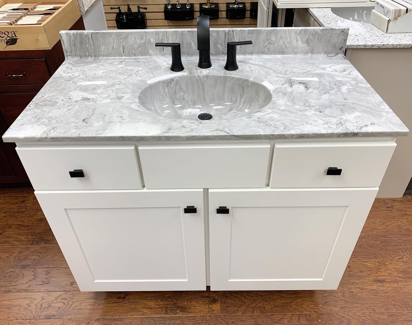 White bathroom vanity with gray granite countertop, black faucet, and hardware.