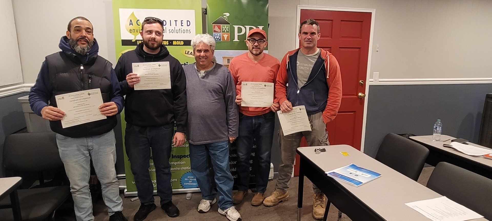 A group of men are standing in a room holding certificates