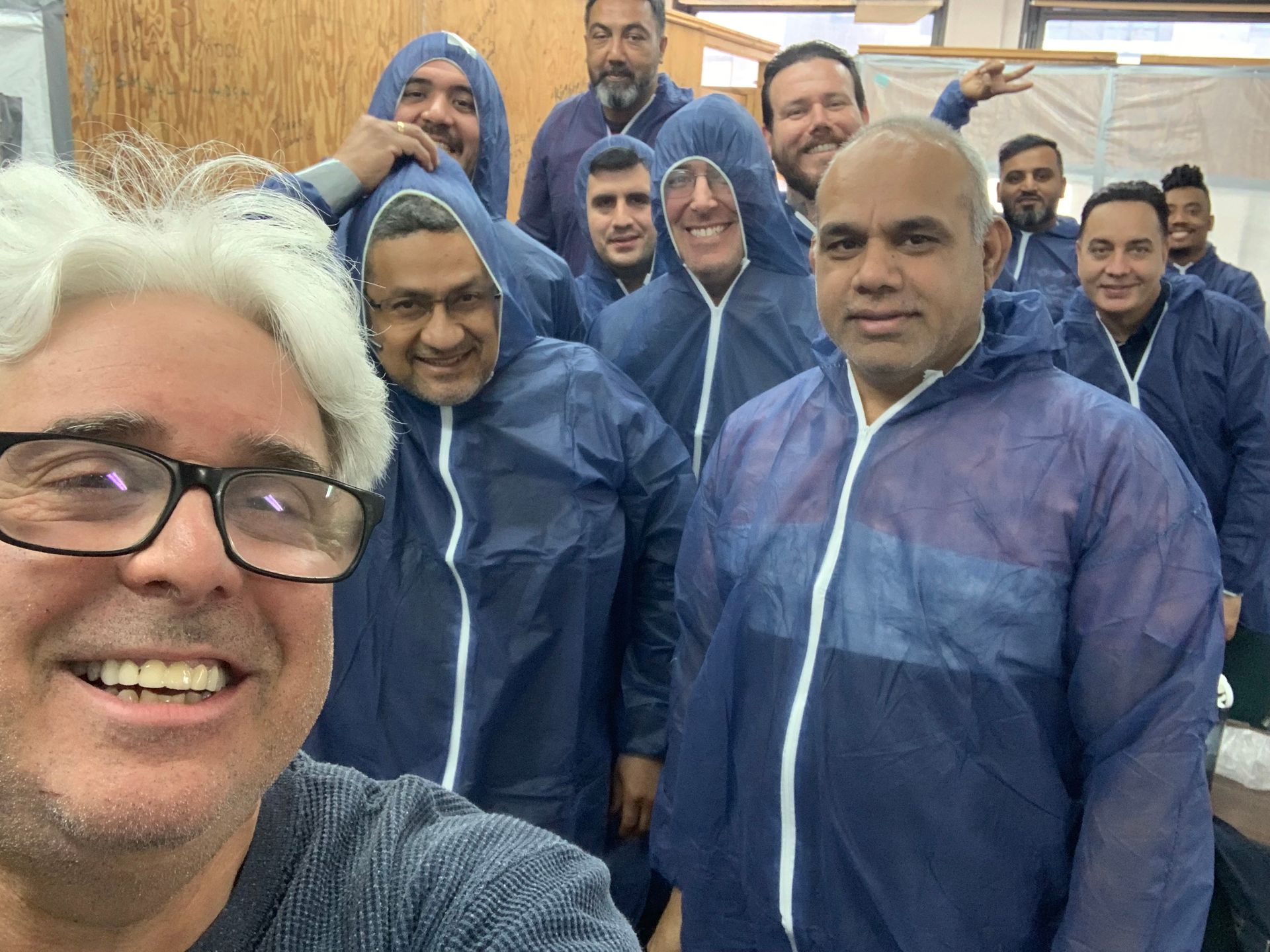 A group of men wearing blue coveralls are posing for a picture