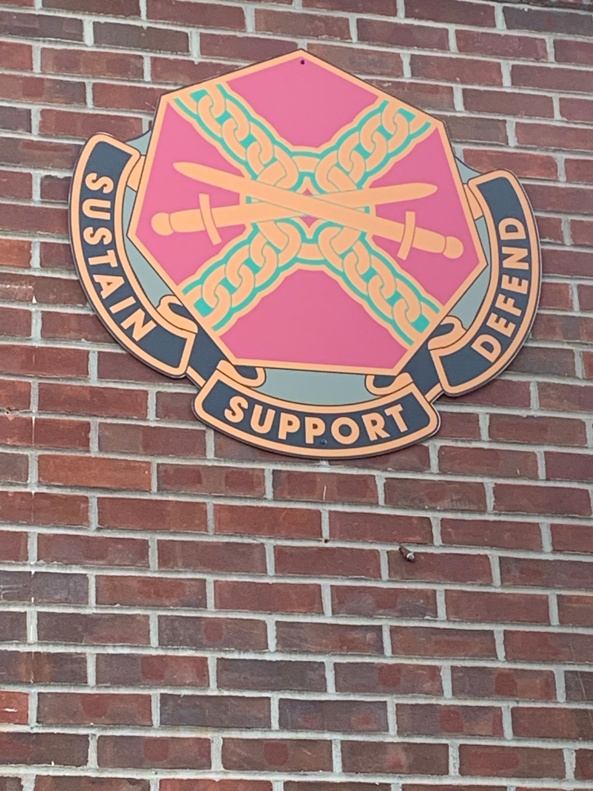 A sign on a brick wall that says Sustain, Support, & Defend