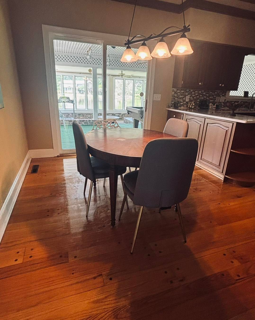 Dining area with wood floor, table, chairs, sliding glass door to a pool, and overhead lighting.