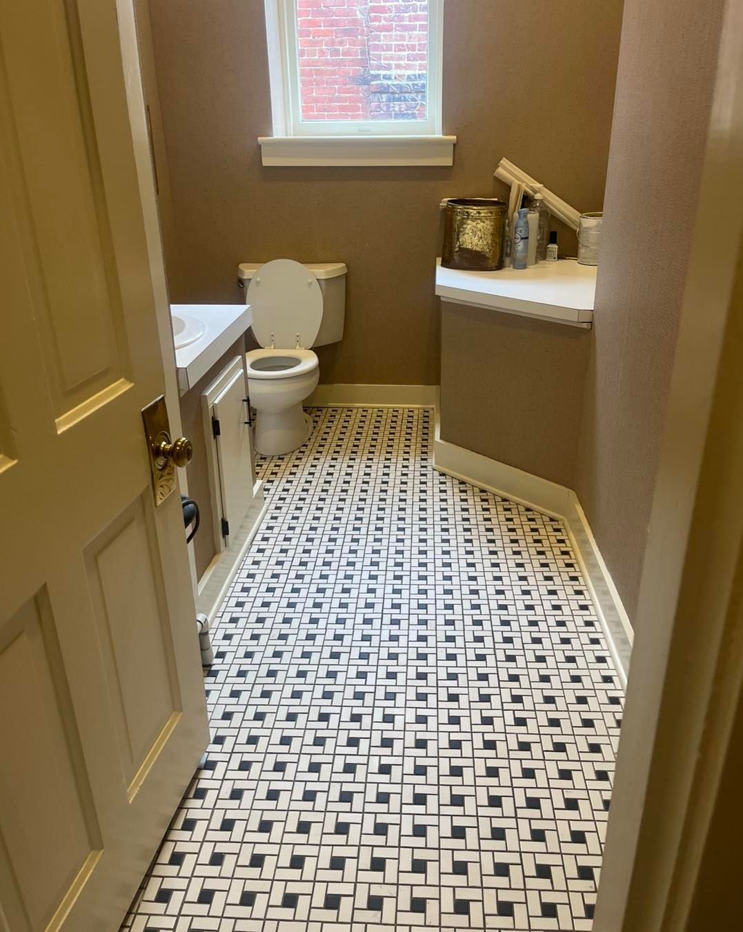 Bathroom with patterned tile floor, white toilet, and beige walls.