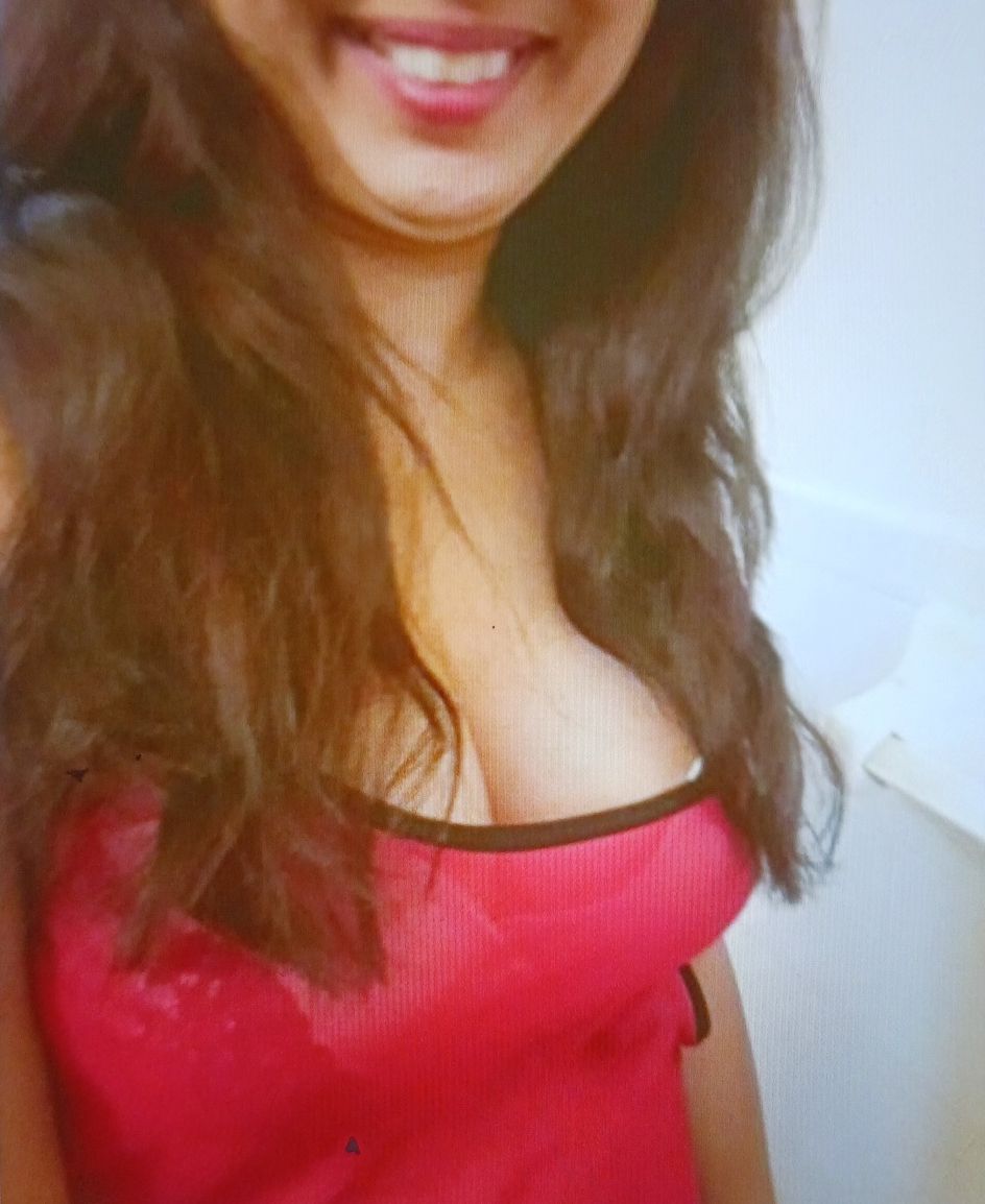 Woman with long dark hair and a red top smiles at the camera.